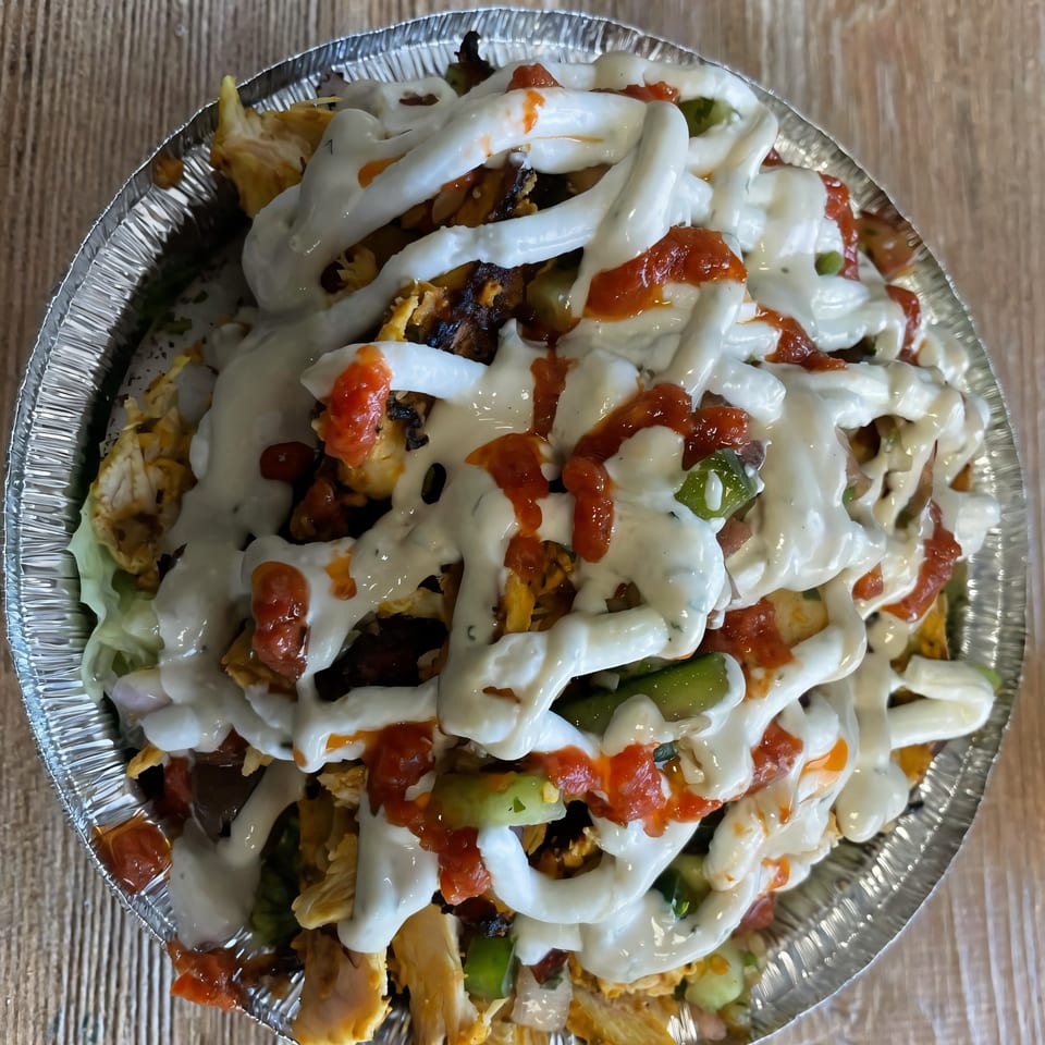 Habibi Mediterranean Grill's chicken and rice bowl topped with white sauce and red chili sauce.