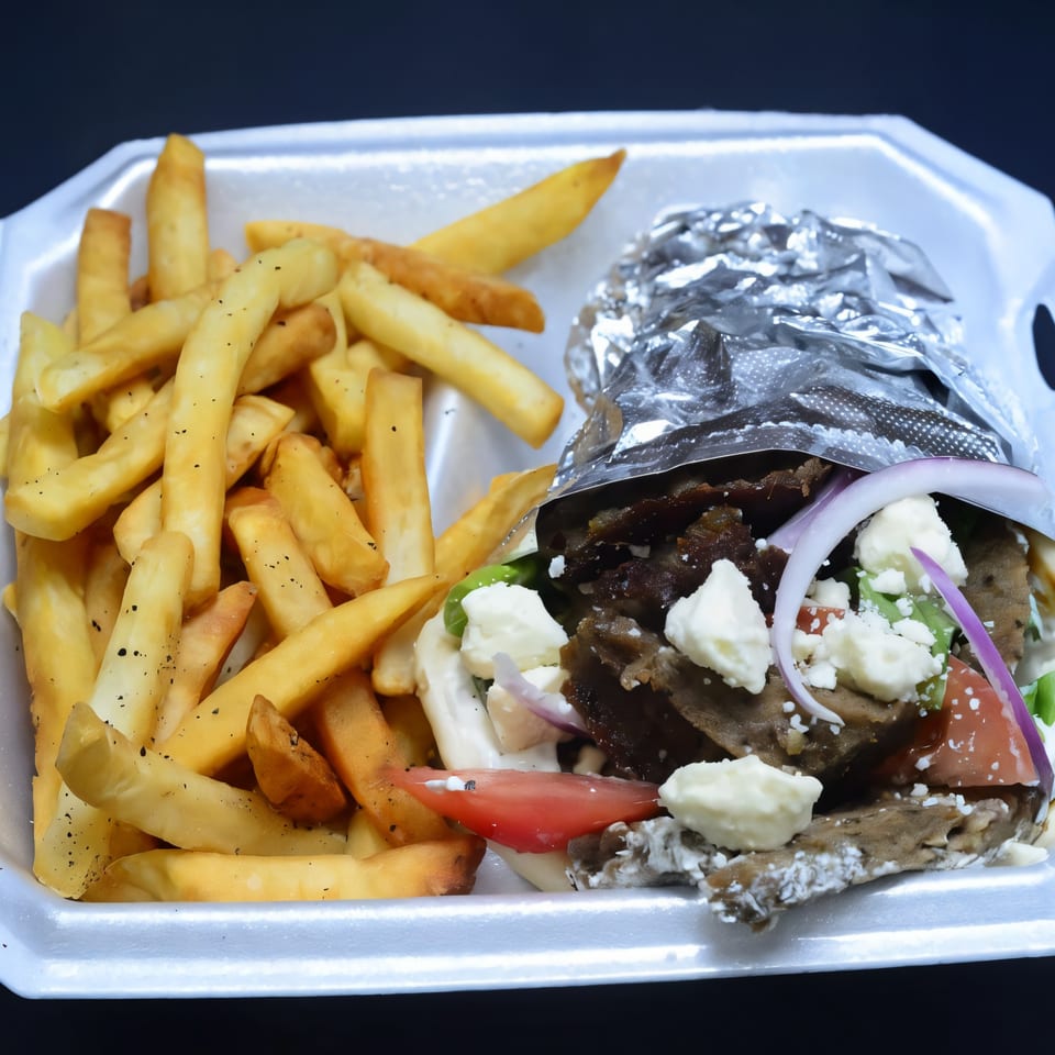 Habibi Mediterranean Grill's gyro with feta, tomatoes, onions, and fries in a white takeout container.